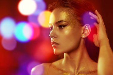 Altın makyaj malzemesi. Siyah arka planda altın makyajlı güzel bir genç kadının portresi. Lüks bir tarz. Kozmetik ve makyaj konsepti.