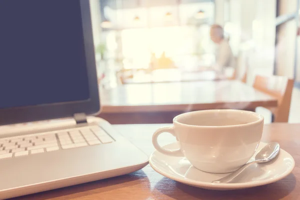 Café con portátil en la mesa de madera en la cafetería . —  Fotos de Stock