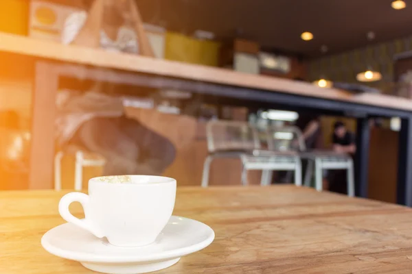Tasse Kaffee mit Rauch auf Holztisch im Café. — Stockfoto