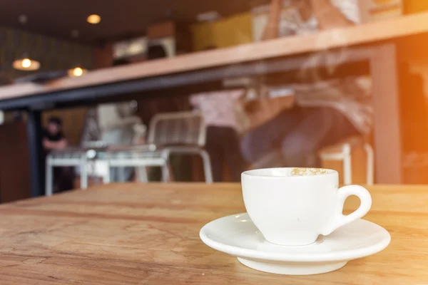 Filiżanka kawy z dymu na drewnianym stole w kawiarni. — Zdjęcie stockowe