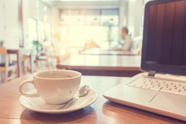 Kawa z laptopa na drewnianym stole w kawiarni. — Zdjęcie stockowe