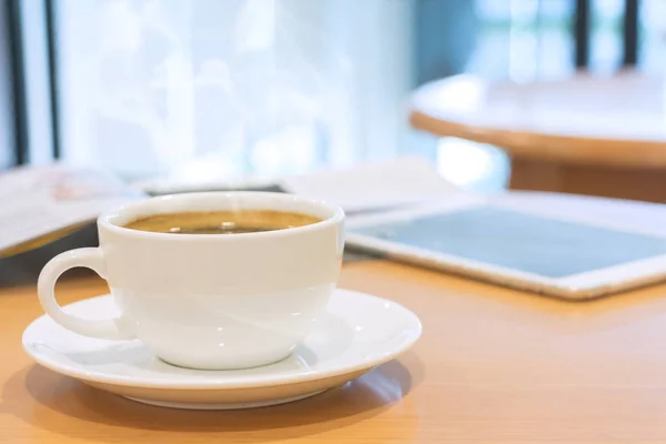 Branco xícara de café com revista e tablet computador em madeira ta — Fotografia de Stock