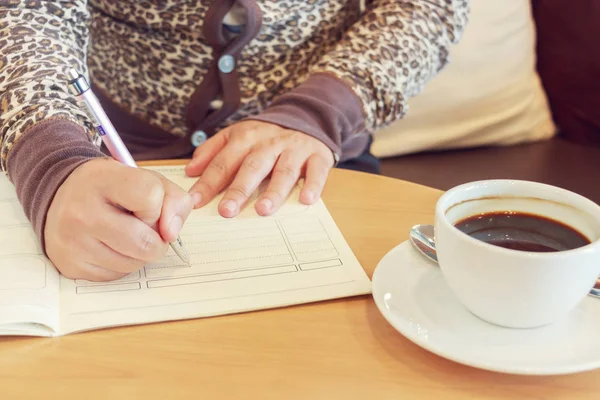 Arbeitende Frau hält einen Stift in der Hand und schreibt auf weißen Zettel — Stockfoto