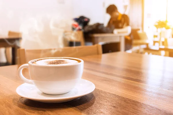 Witte kopje koffie met rook op tafel in café. — Stockfoto