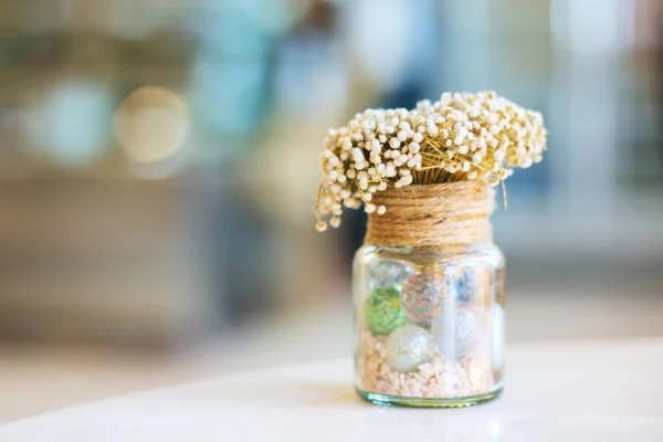 Dried flowers in glass bottle on wood table decorations in cafe.