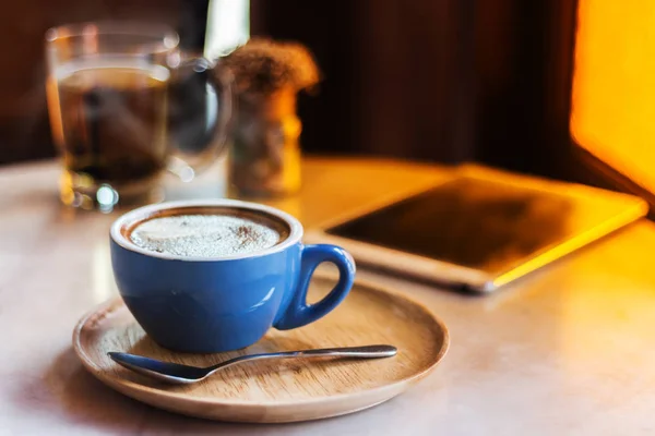 Kaffeetasse auf Tisch mit Tablet im Café-Shop. — Stockfoto