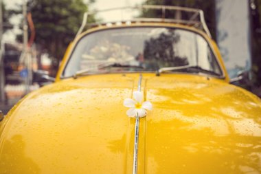 flower power - old stylish yellow hippy car with flower on the bonnet or hood clipart