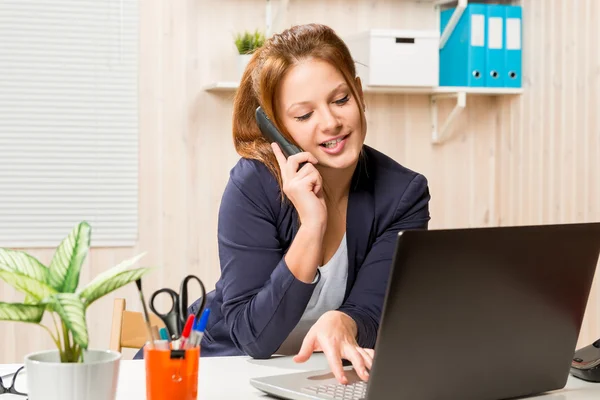 Manager talking on the phone and working on the computer in the — Stock Photo, Image