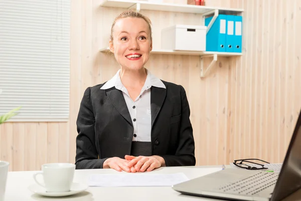 Pretty cheerful woman in a suit behind a computer — Stock Photo, Image