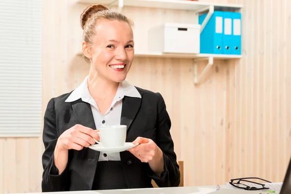 Economista sonriendo con una taza de café en una mesa en la oficina —  Fotos de Stock