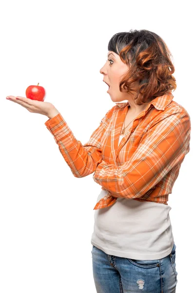 Young woman looking at a red apple with a astonishment against w — Stock Photo, Image