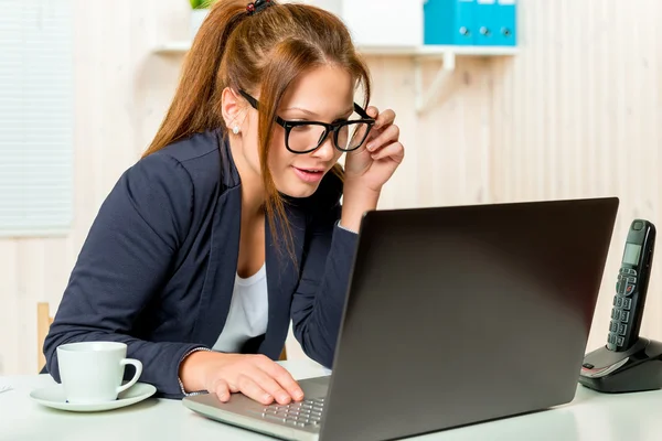 Hermosa secretaria escanea cuidadosamente el correo electrónico en el ordenador en el Fotos de stock libres de derechos