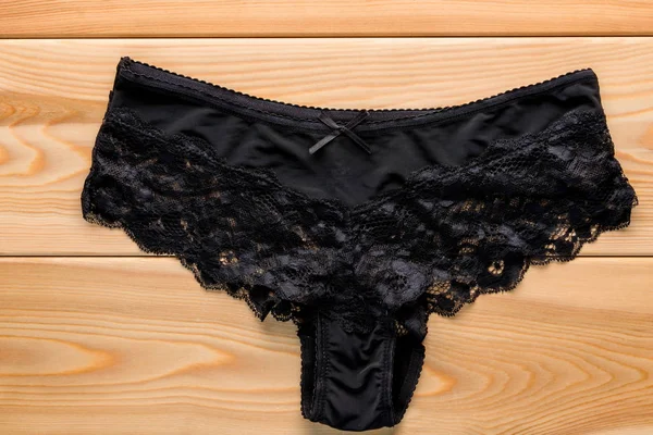 Feminine satin panties with lace in black on the wooden floor cl — Stock Photo, Image