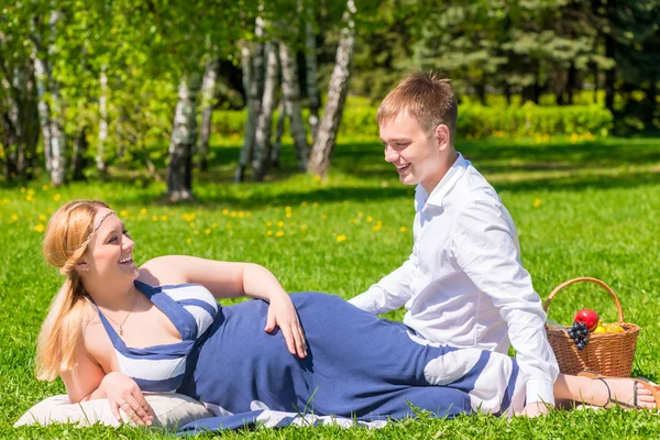 Jovem casal grávida em um dia ensolarado, relaxar no gramado — Fotografia de Stock