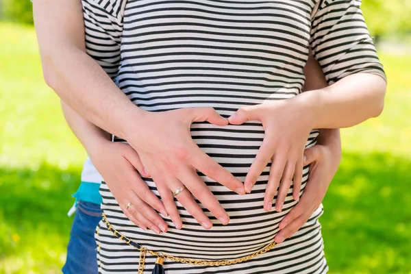 Vientre y manos embarazadas en forma de corazón en el vientre expectante —  Fotos de Stock