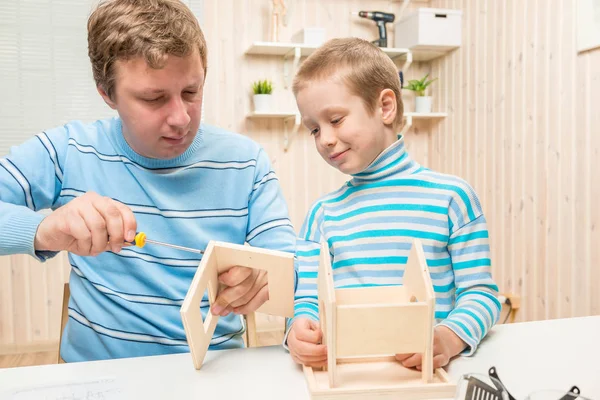 Vader geeft zijn zoon hoe het bouwen van een vogel feeder — Stockfoto