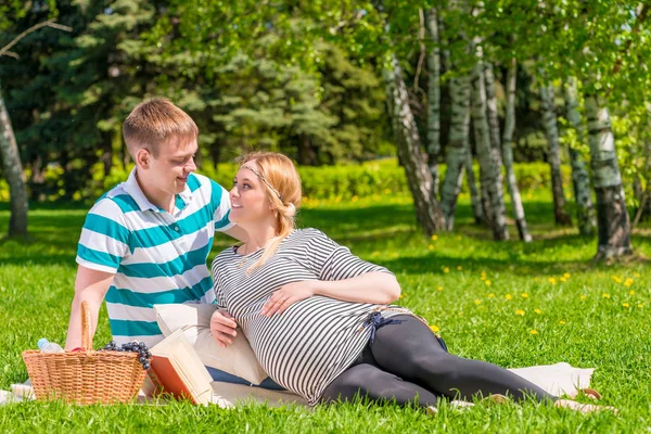 Pregnant couple resting on the plaid in the park — Stock Photo, Image