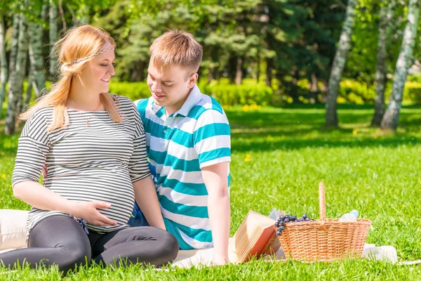 Familia joven descansando en un parque en un picnic, la chica con un gran — Foto de Stock