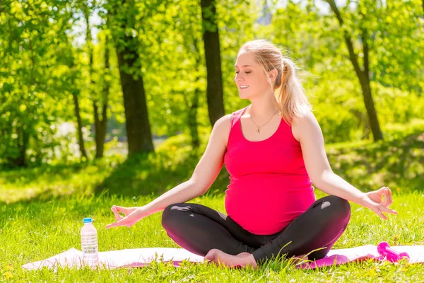 Unga gravid kvinna i lotusställning gör yoga och avslappning — Stockfoto