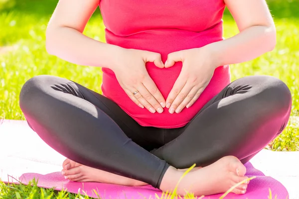Manos en forma de corazón sobre el vientre de una mujer embarazada c — Foto de Stock