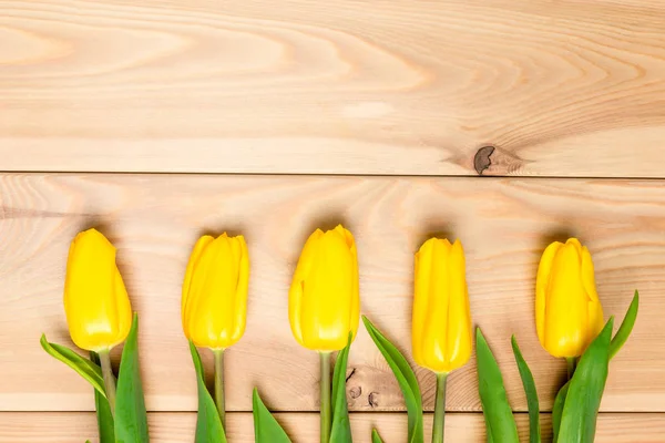 Rij met gele tulpen op een houten achtergrond close-up — Stockfoto