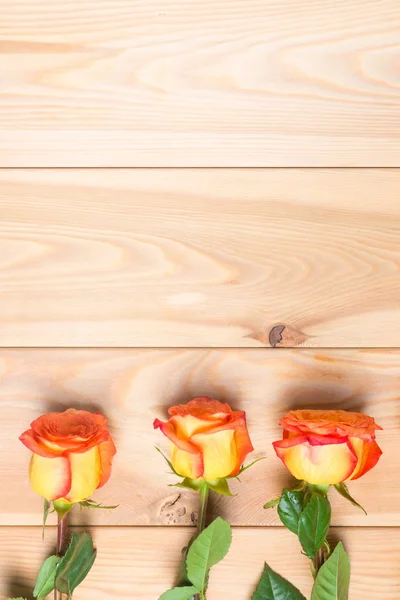Três rosas em uma tábua de madeira e espaço de cópia no topo — Fotografia de Stock