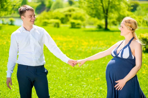 La mujer embarazada y su marido mantuvieron la mano en el parque — Foto de Stock