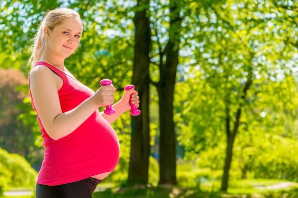 Gravid kvinna Utomhus i parken med hantlar — Stockfoto