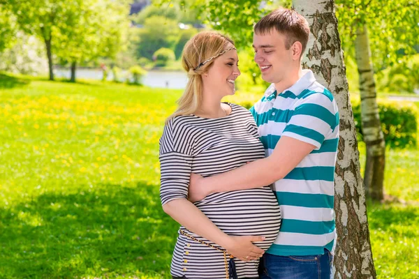 Joven abrazando a su hermosa esposa embarazada en el parque — Foto de Stock