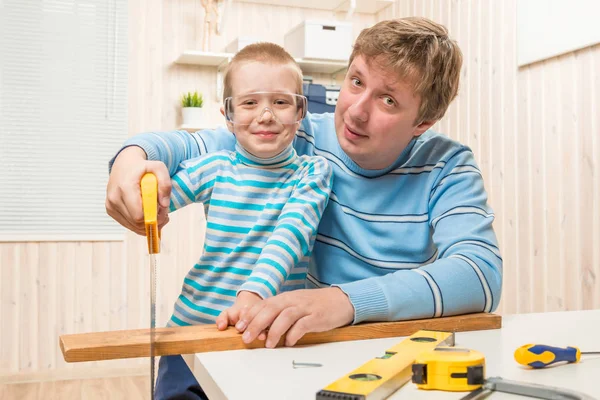 Vader leert zijn zoon te snijden van de houten plank zaag — Stockfoto