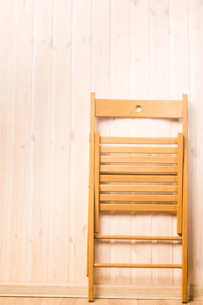 Vertical shot of a folding chair near the wall in the room — Stock Photo, Image