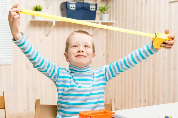 6 jaar oude jongen in de garage met een meetlint — Stockfoto