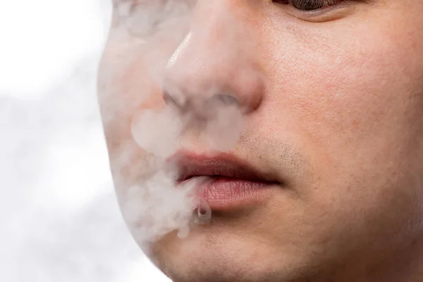 Cigarettrök och en mans ansikte som närbild på en vit bakgrund — Stockfoto