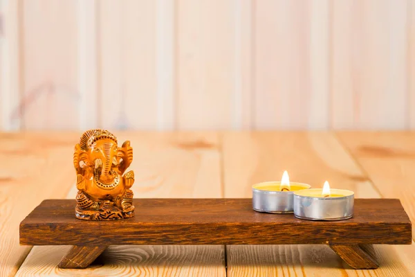 Estatuilla de madera del dios Ganesha y una vela sobre un soporte —  Fotos de Stock