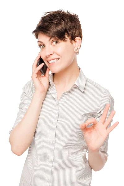Young brunette with a phone on a white background isolated — Stock Photo, Image