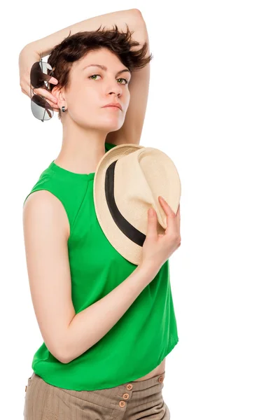 Brunette holding hat and sunglasses on a white background in stu — Stock Photo, Image