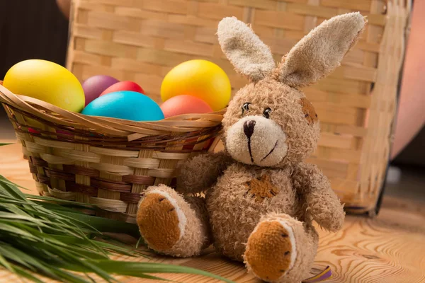 Leksak Påskharen och färgade ägg i en korg-närbild — Stockfoto
