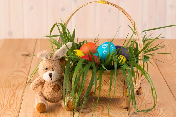 Paashaas en mand met geschilderde paaseieren op houten bord — Stockfoto