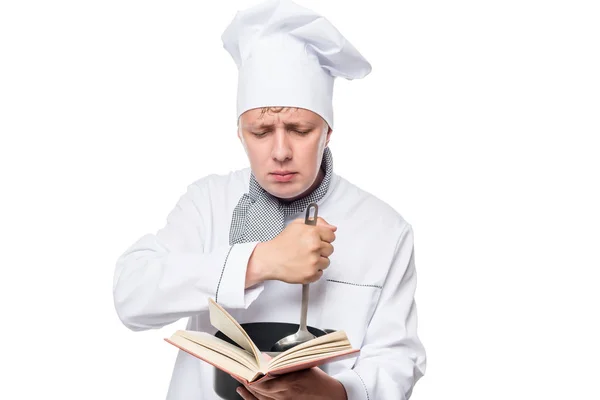 Помощник повара хочет быть шеф-поваром, читающим книгу рецептов на Whi — стоковое фото