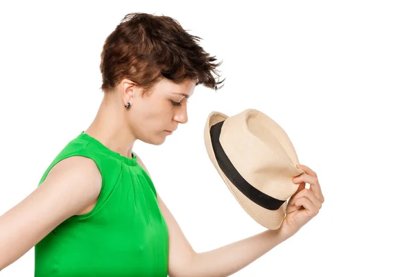 Young girl with short hair holding a hat on a white background — Stock Photo, Image