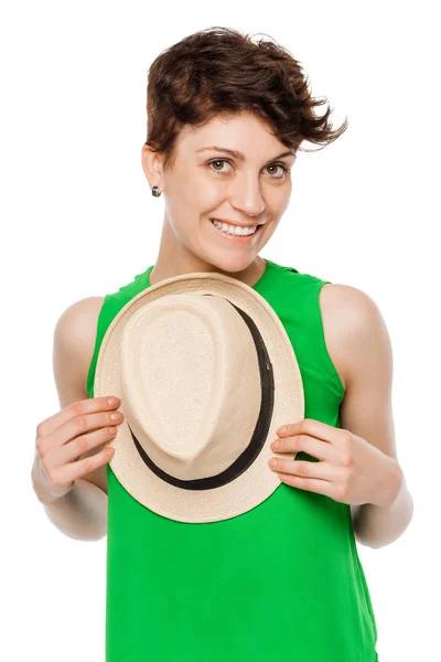 Милая брюнетка в зеленом топе, держащая шляпу на белой спинке — стоковое фото