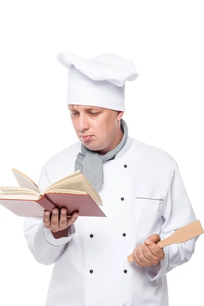 Aprendiz de chef con una pala en la mano leyendo un libro sobre un wh —  Fotos de Stock