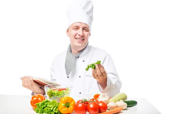 Cook happy face at the table with salad and a book of recipes on — Stock Photo, Image