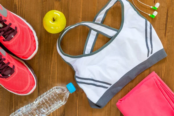 Op een donkere houten vloer kinderkleding sport objecten en vrouwen top v — Stockfoto