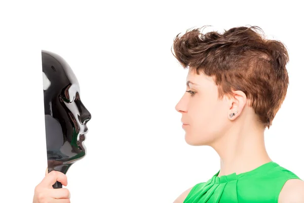 Woman looking at a glossy black mask on a white background — Stock Photo, Image