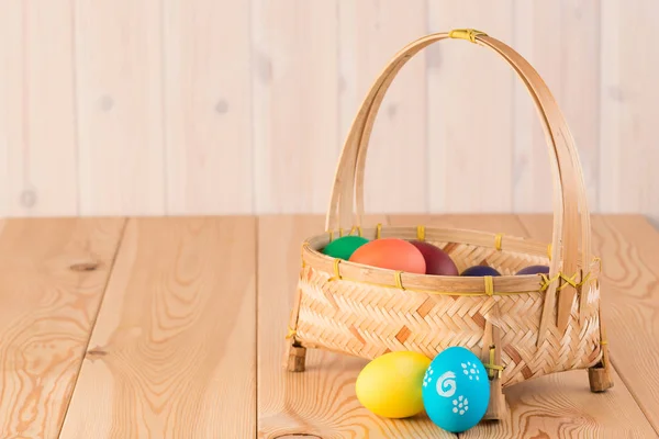 Лаконичная пасхальная композиция - корзина с цветными яйцами на дереве — стоковое фото