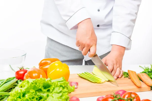Шеф розрізає салат, готує свіжі овочі на білому тлі — стокове фото