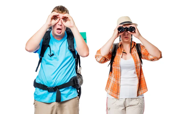 Young couple with backpacks looking in binoculars on white backg — Stock Photo, Image