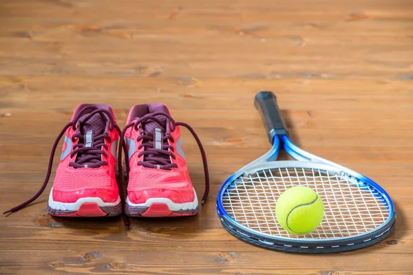 Set for playing tennis - sneakers, racket and ball on the floor