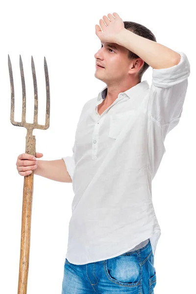 Agricultor em uma camisa branca com uma forquilha na mão limpando o — Fotografia de Stock